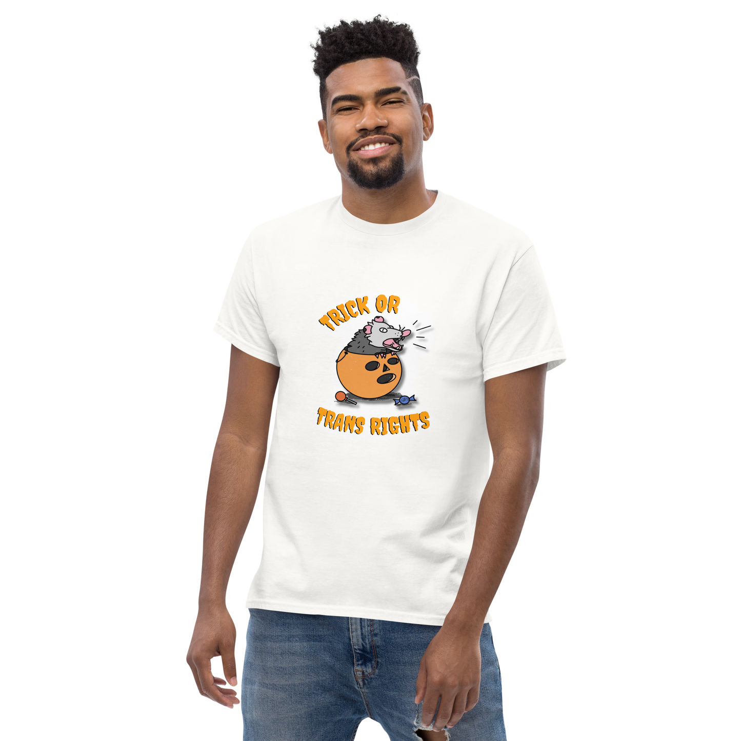 This design features a possum in an orange plastic candy bucket with the text "Trick or Transphobia" on a white t-shirt. This image is the shirt design on a standard sized model.