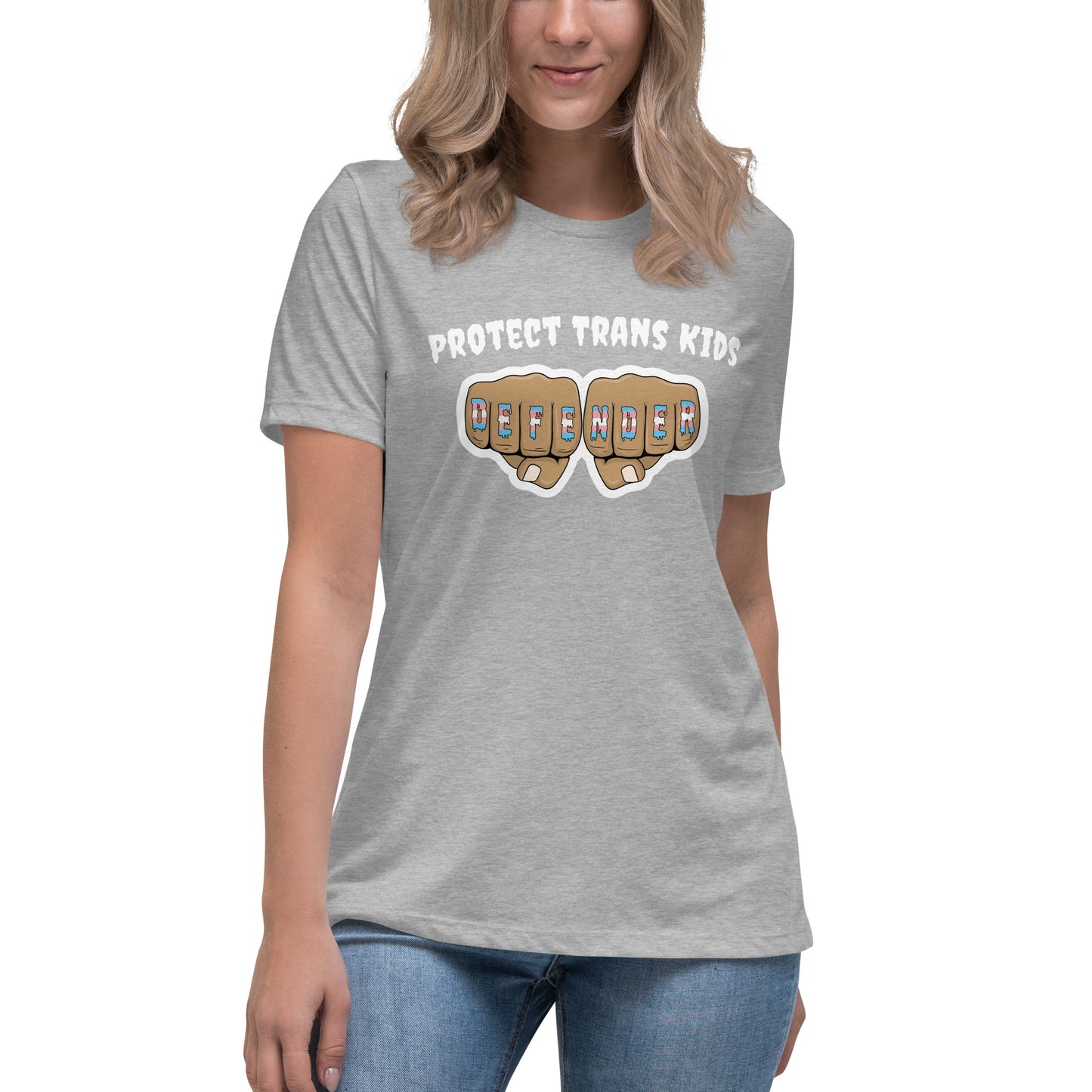 A standard, round neck, short sleeve t-shirt in light heather greywith the text "protect trans kids" in white lettering above an image of fists with "defender" written across the knuckles in blue,pink, and white. The shirt is on a white, straight sized model standing against a white background.