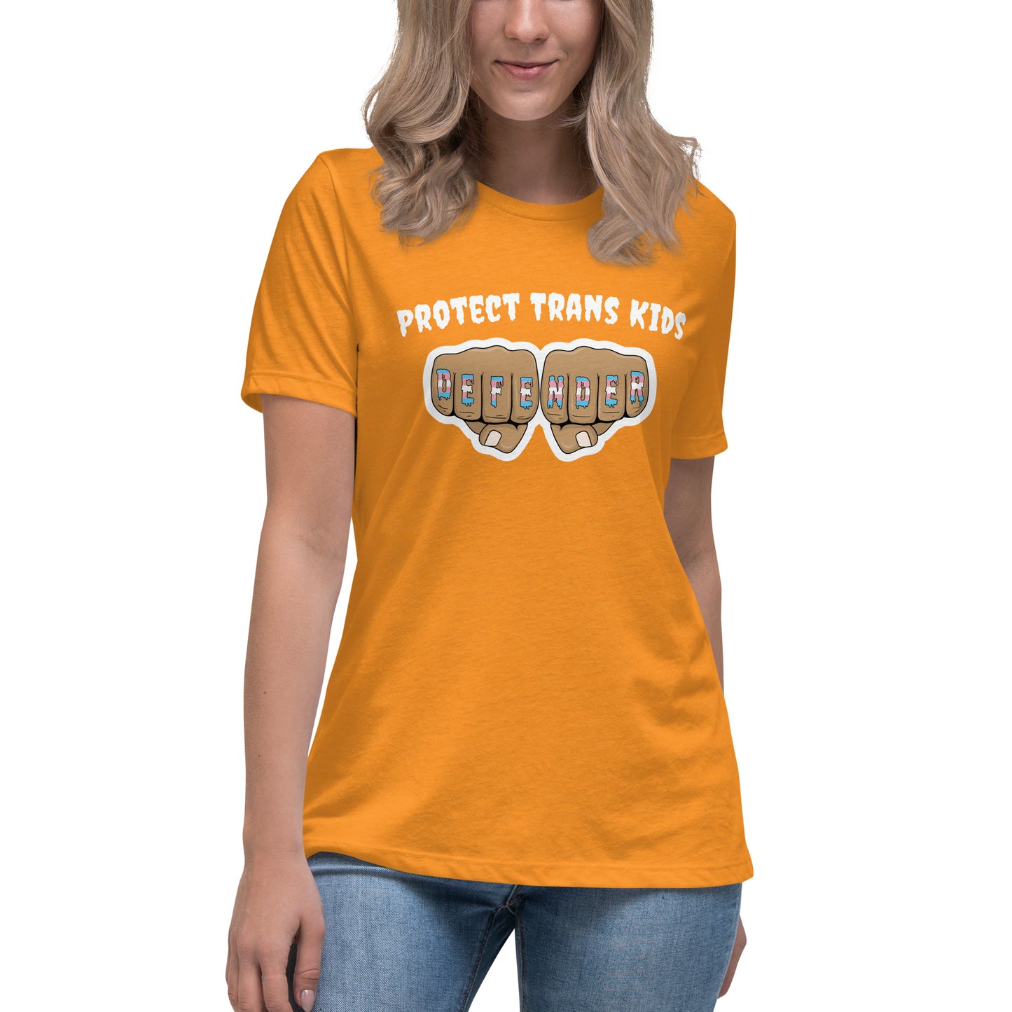A standard, round neck, short sleeve t-shirt in bright orange with the text "protect trans kids" in white lettering above an image of fists with "defender" written across the knuckles in blue, pink, and white. The shirt is on a white, straight sized model standing against a white background.