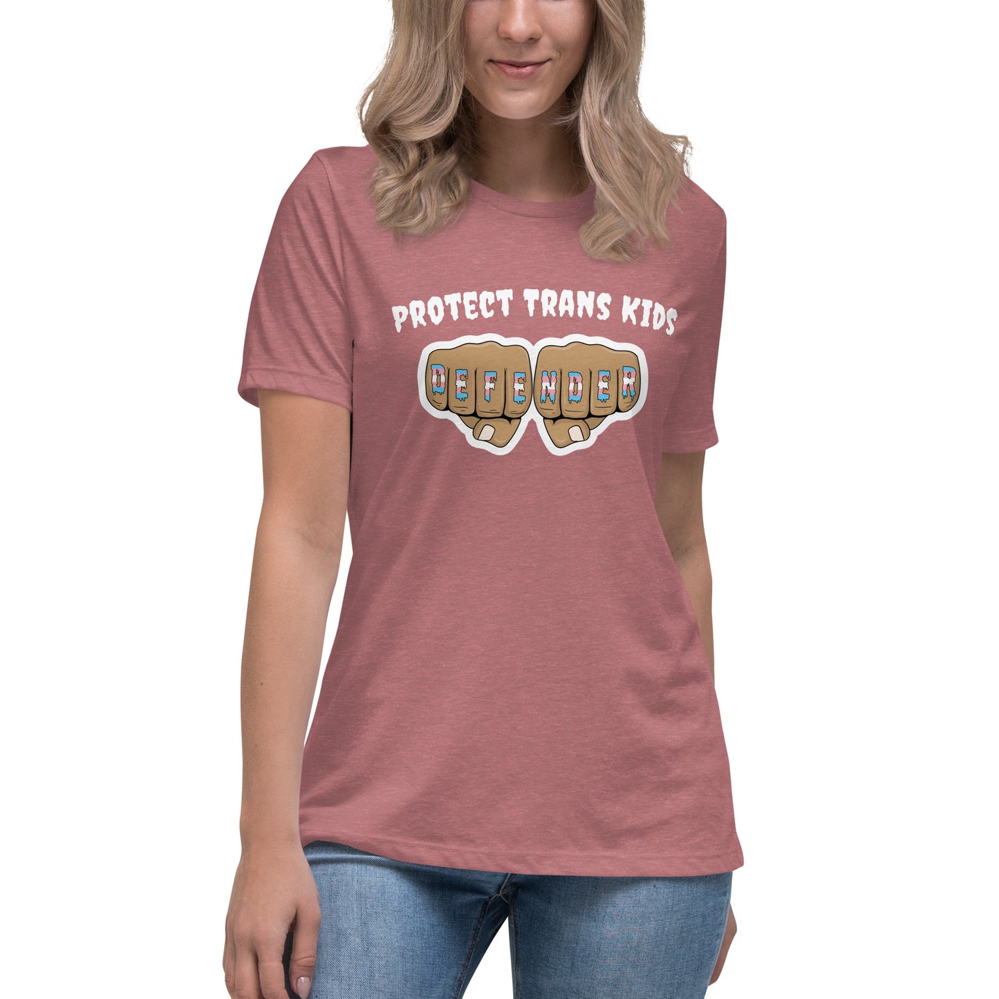 A standard, round neck, short sleeve t-shirt in pink heather with the text "protect trans kids" in white lettering above an image of fists with "defender" written across the knuckles in blue,pink, and white. The shirt is on a white, straight sized model standing against a white background.