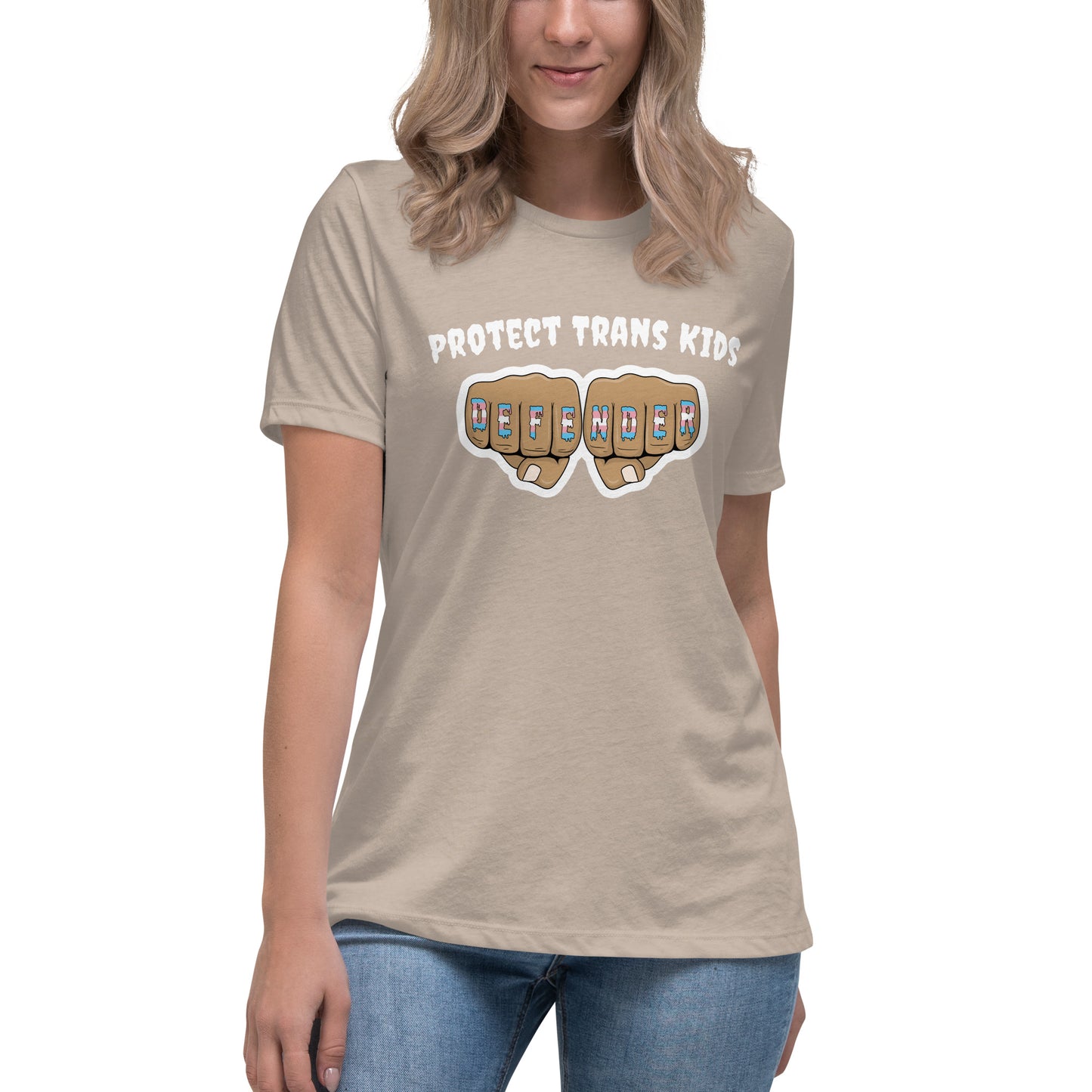 A standard, round neck, short sleeve t-shirt in tan with the text "protect trans kids" in white lettering above an image of fists with "defender" written across the knuckles in blue,pink, and white. The shirt is on a white, straight sized model standing against a white background.