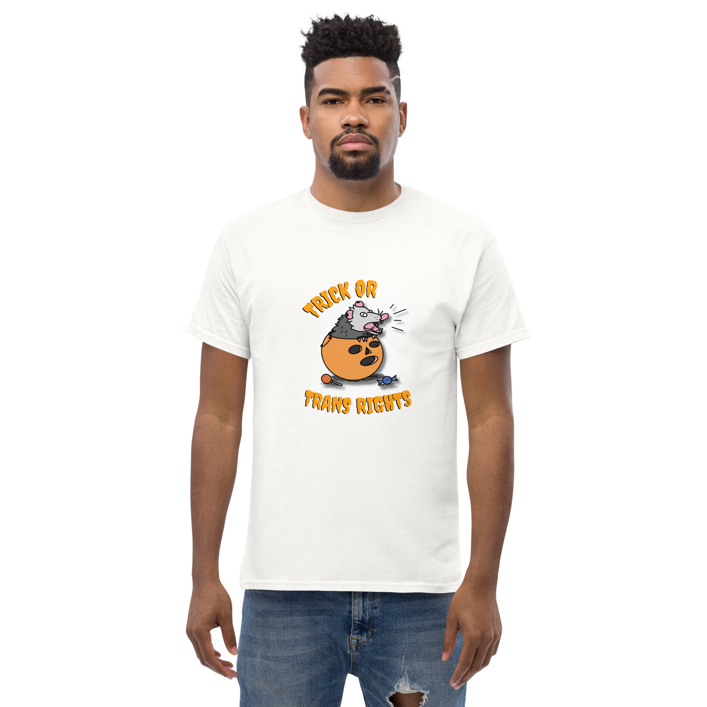 This design features a possum in an orange plastic candy bucket with the text "Trick or Transphobia"  on a white t-shirt. This image is the shirt design on a standard sized model.